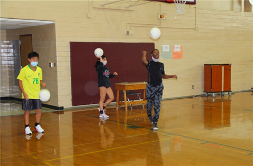 Students practice serving volleyball 